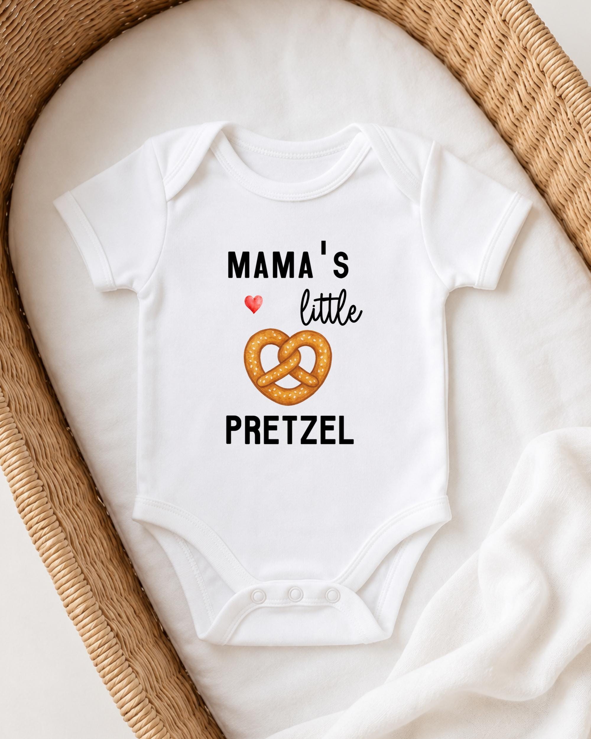 A white baby onesie with the text "MAMA'S LITTLE PRETZEL" printed on it, along with an illustration of a pretzel.