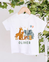 A white t-shirt with a graphic design featuring a giraffe, elephant, and other animals wearing party hats, along with the name "OLIVER" written on the shirt.