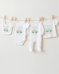 A collection of baby clothes and bibs, including onesies and bibs, hanging on a clothesline.
