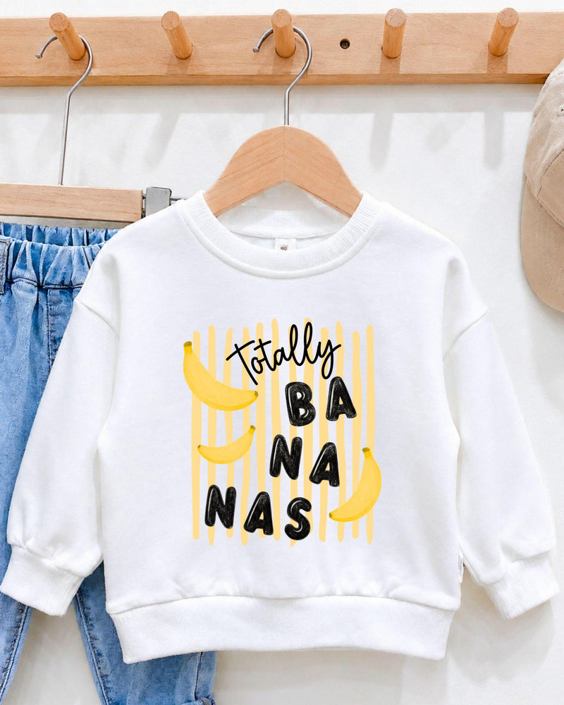 A white sweatshirt with a playful graphic design featuring bananas and the text "Totally BANANA" printed on it.