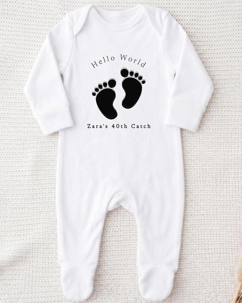 A white bodysuit with a black footprint design and text printed on it.