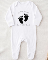 A white onesie with a black footprint design and text printed on it.