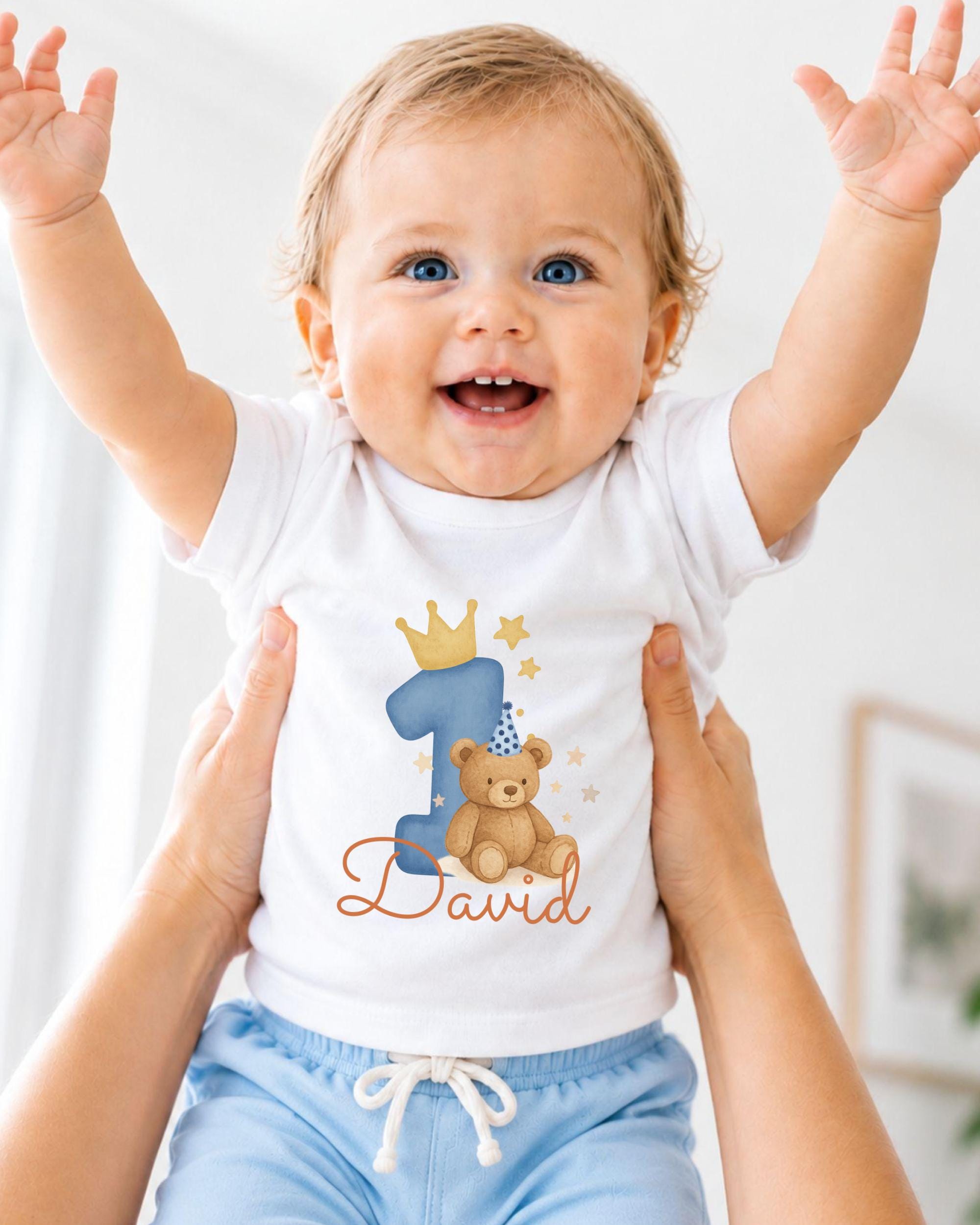 A smiling baby wearing a white t-shirt with a teddy bear and the number 1, with the name "David" written below.