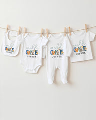A collection of white baby clothes, including onesies and bibs, hanging on a clothesline.
