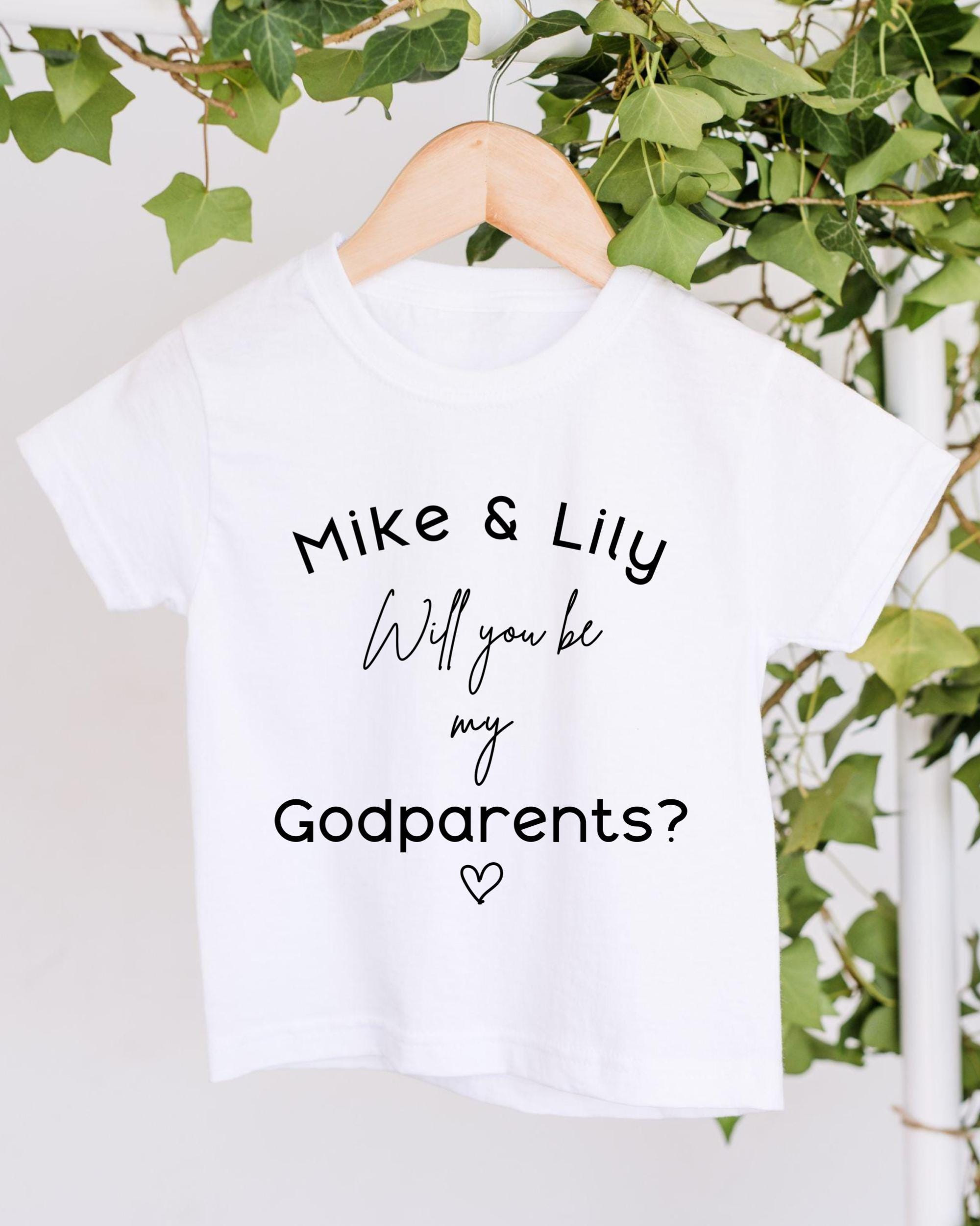 A white t-shirt with text printed on it, hanging on a wooden hanger.