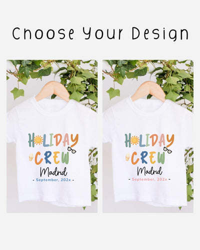 two white t-shirts with colorful text and graphics, hanging on a wooden hanger. The text on the t-shirts reads "HOLIDAY CREW Madrid" and "September, 20xx".