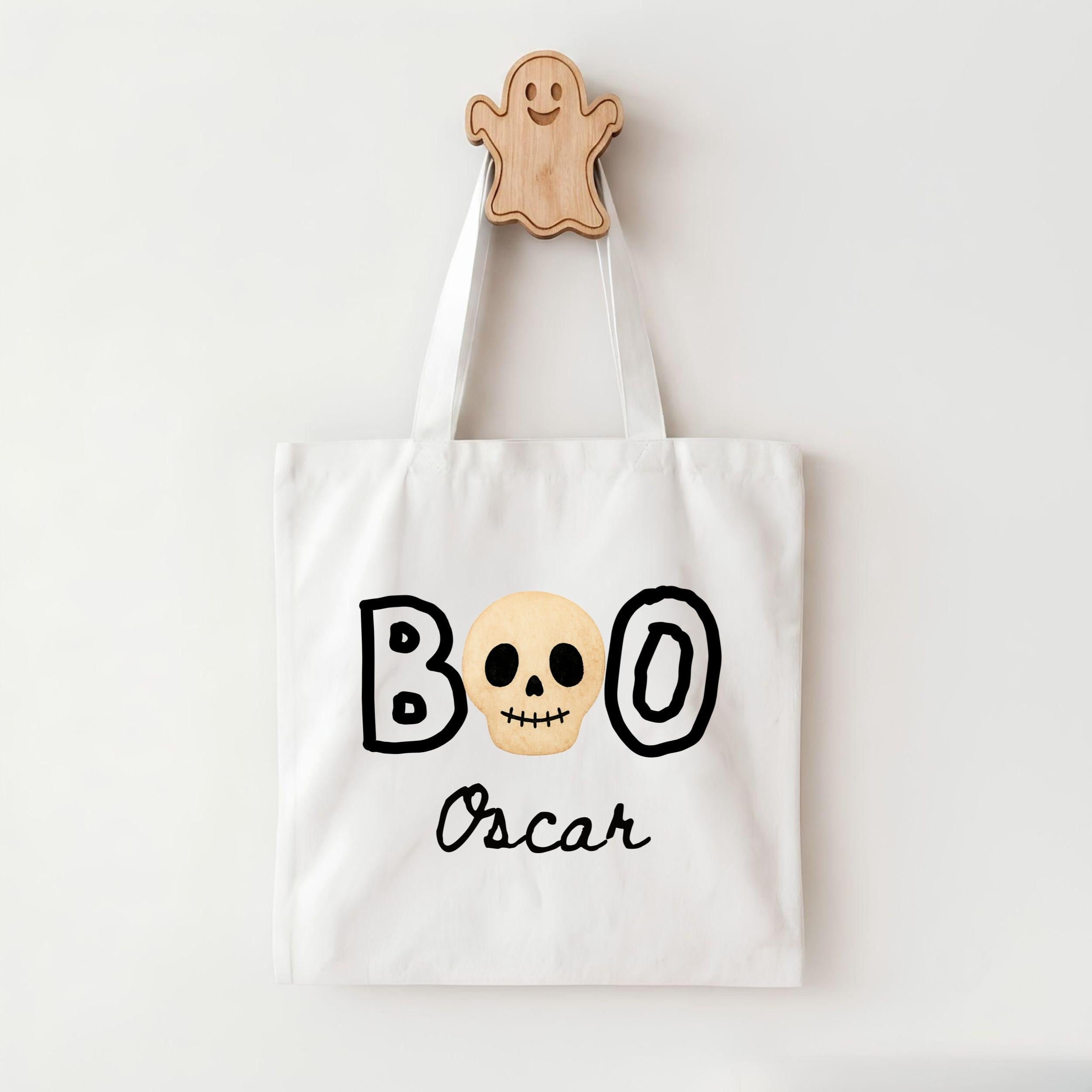 A white tote bag with the text "BOO Oscar" printed on it, along with a skull and ghost design.