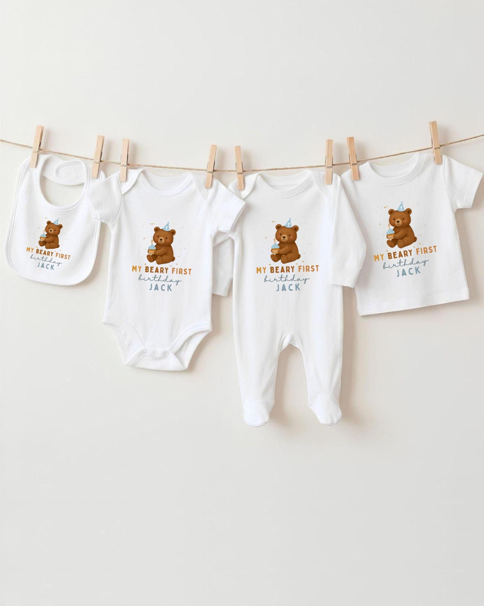 A collection of baby clothes, including onesies and bibs, hanging on a clothesline.