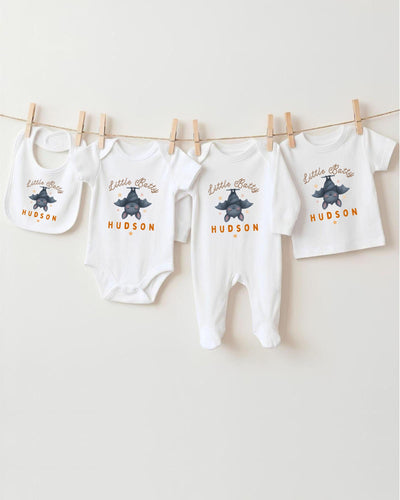 A collection of baby clothes, including bodysuits and bibs, hanging on a clothesline.