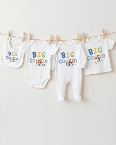 A collection of baby clothes, including bodysuits and bibs, hanging on a clothesline.