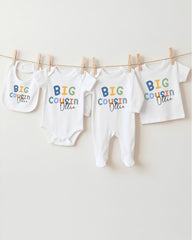 A collection of baby clothes, including onesies and bibs, hanging on a clothesline.