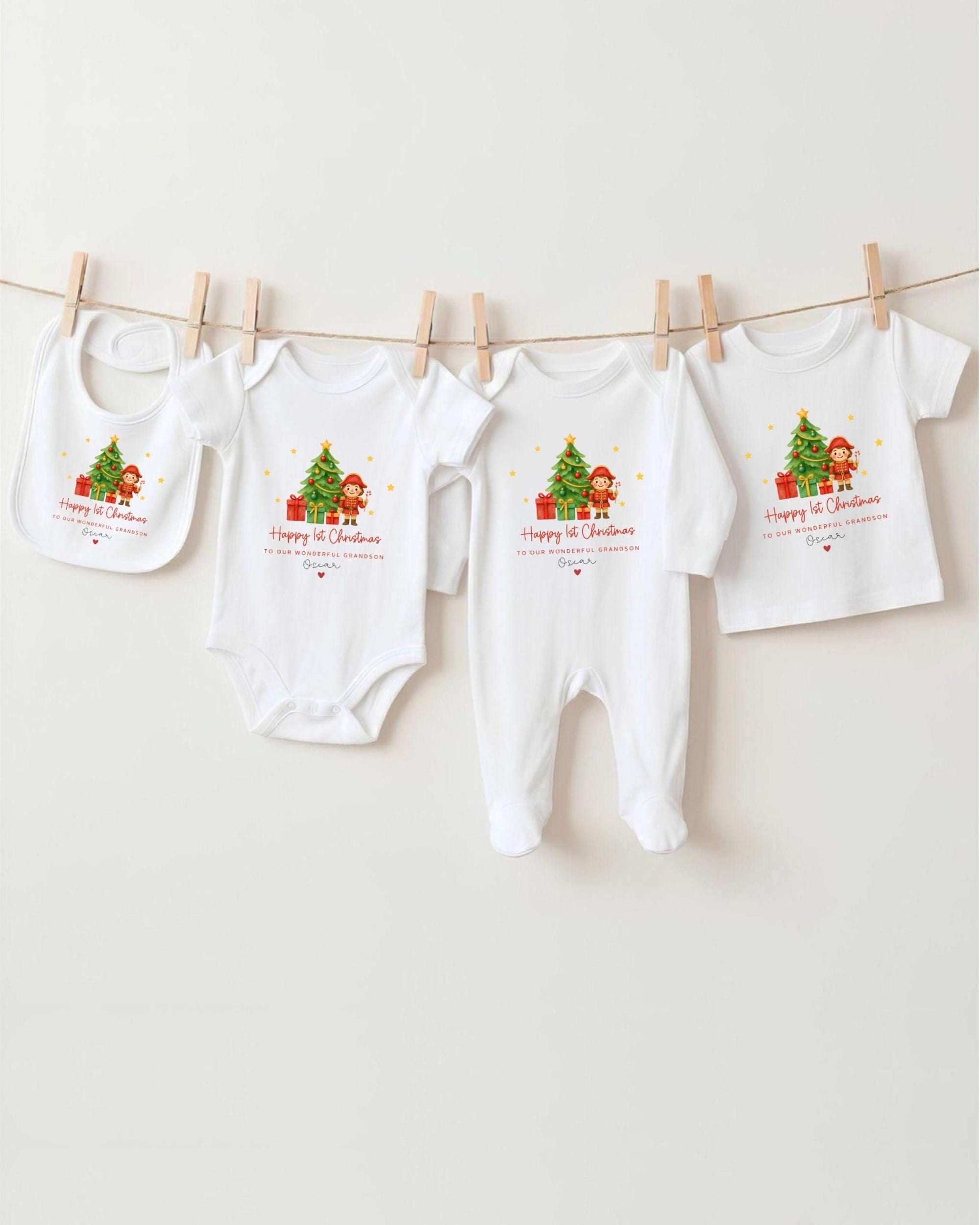 A collection of white baby clothes, including onesies and bibs, hanging on a clothesline. The clothes feature festive Christmas-themed designs, including a Christmas tree and presents.