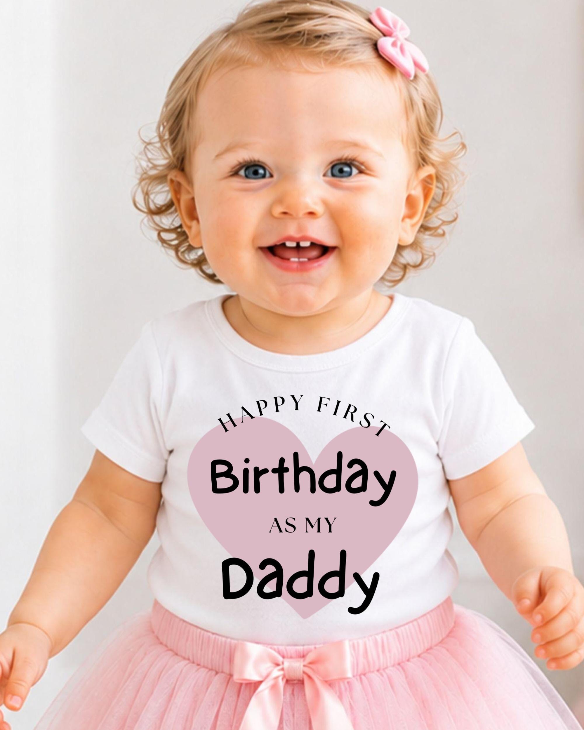 A smiling baby girl wearing a white t-shirt with text and a pink heart, standing in front of a white background.