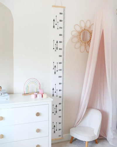 a child's room with a white dresser and pink curtains