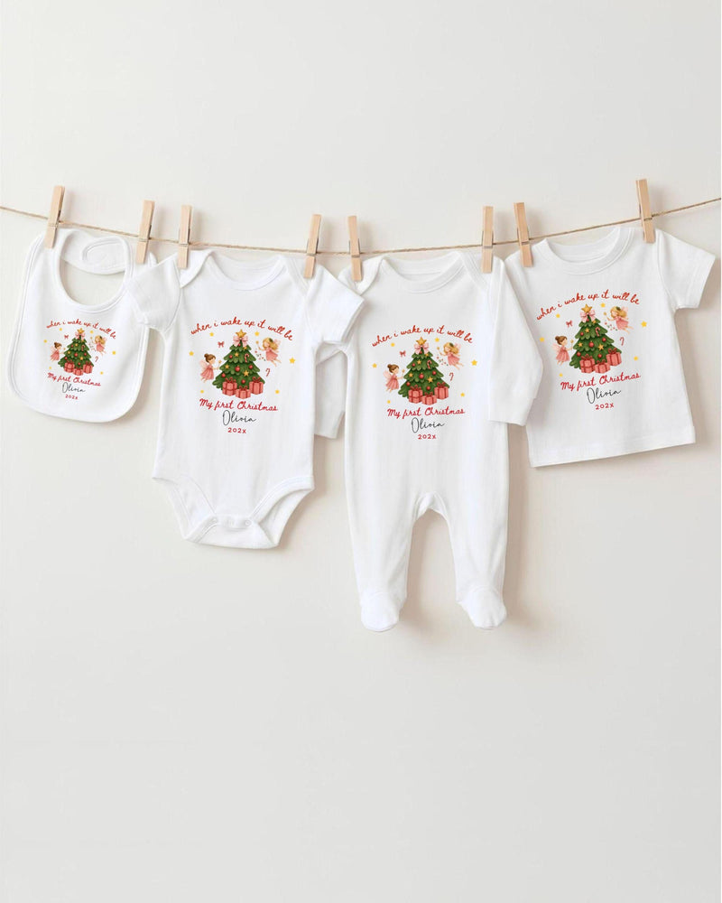 A row of white baby clothes with Christmas-themed designs hanging on a clothesline.