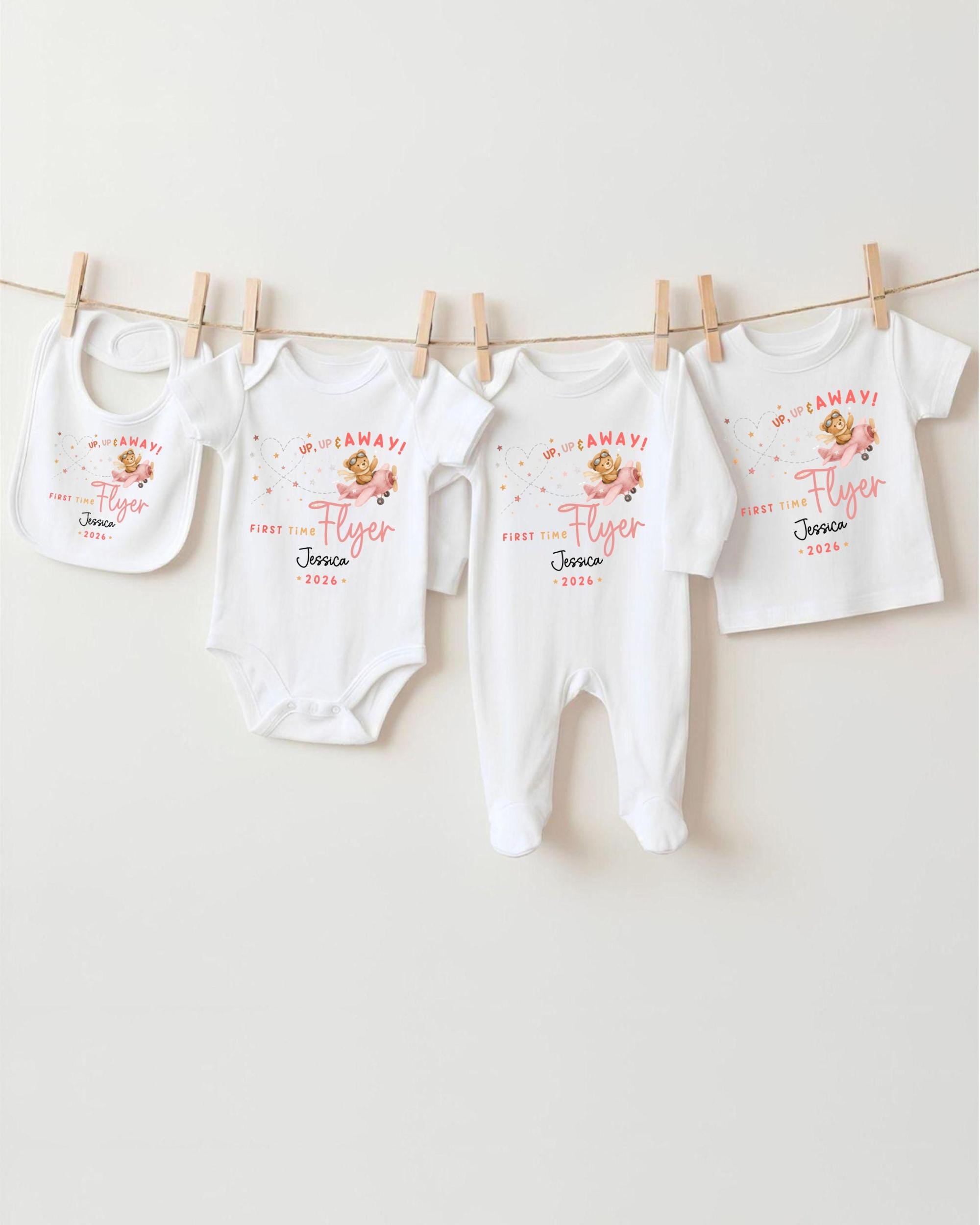 A row of four white baby clothes, including onesies and bibs, hanging on a clothesline.