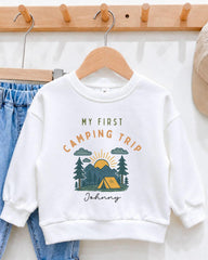 A white sweatshirt with a graphic design and text printed on it, hanging on a wooden hanger.