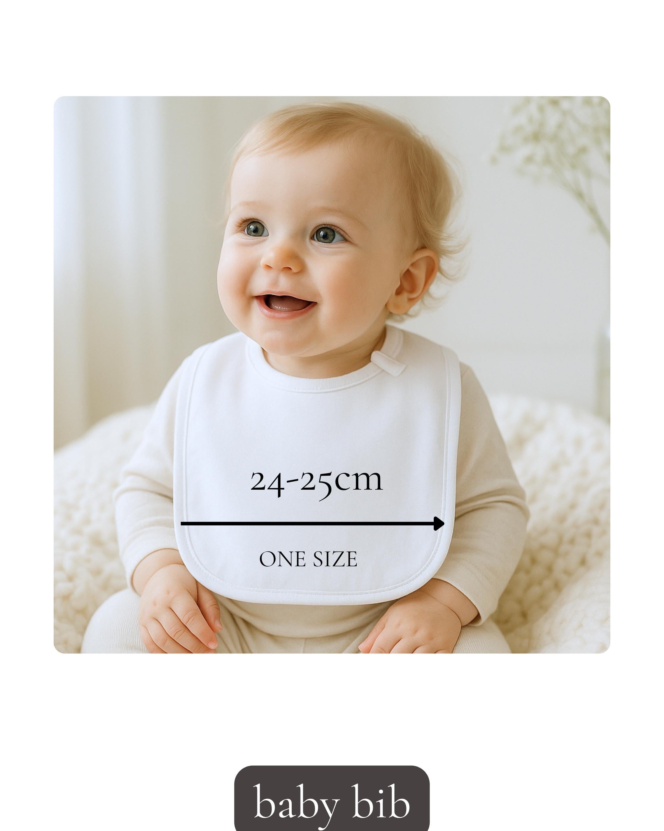 A smiling baby wearing a white bib with measurements and the text "ONE SIZE" is sitting on a white blanket.