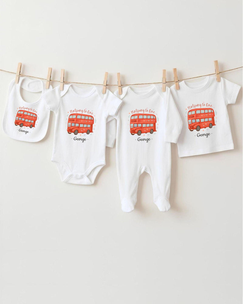 A row of four white baby clothes with red double-decker bus designs, each with a personalized name printed on it.