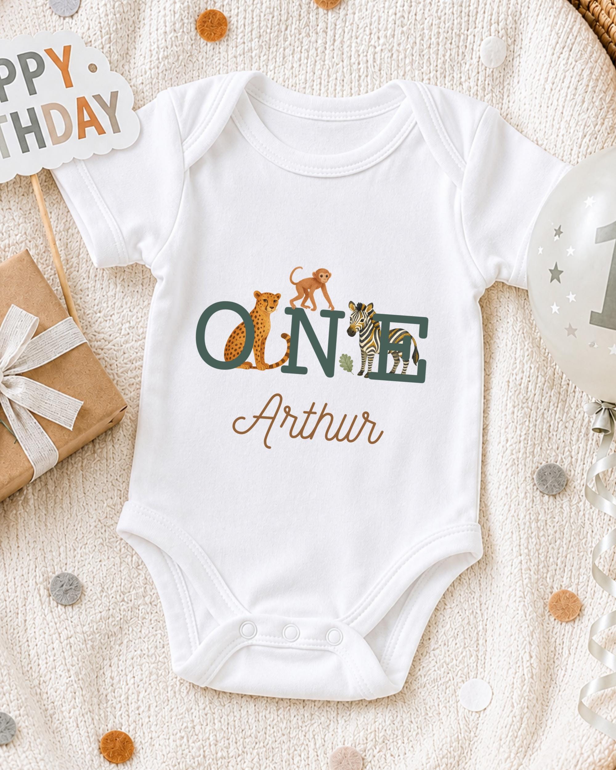 A white onesie with the name "Arthur" printed on it, surrounded by various baby-related items such as a gift box, a balloon, and confetti.