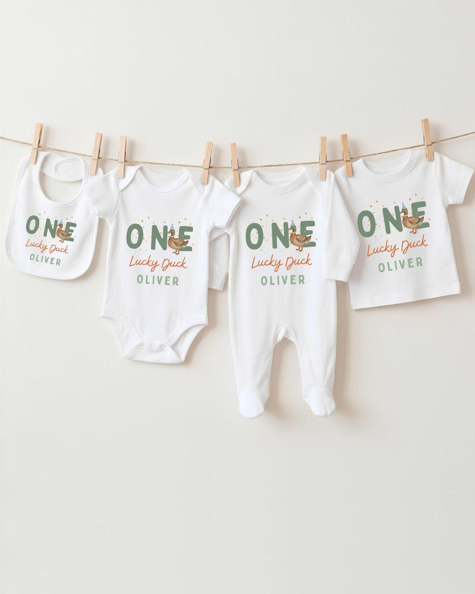 A row of white baby clothes with the name "OLIVER" printed on them, hanging on a clothesline.