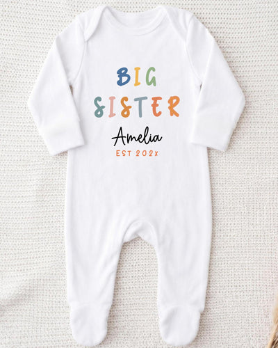 A white bodysuit with the text "BIG SISTER Amelia EST 202x" printed on it.