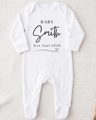 A white onesie with the text "BABY Smith Due Sept 2028" printed on it.