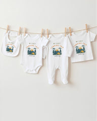 A collection of four white baby clothes, including onesies and bibs, hanging on a clothesline.