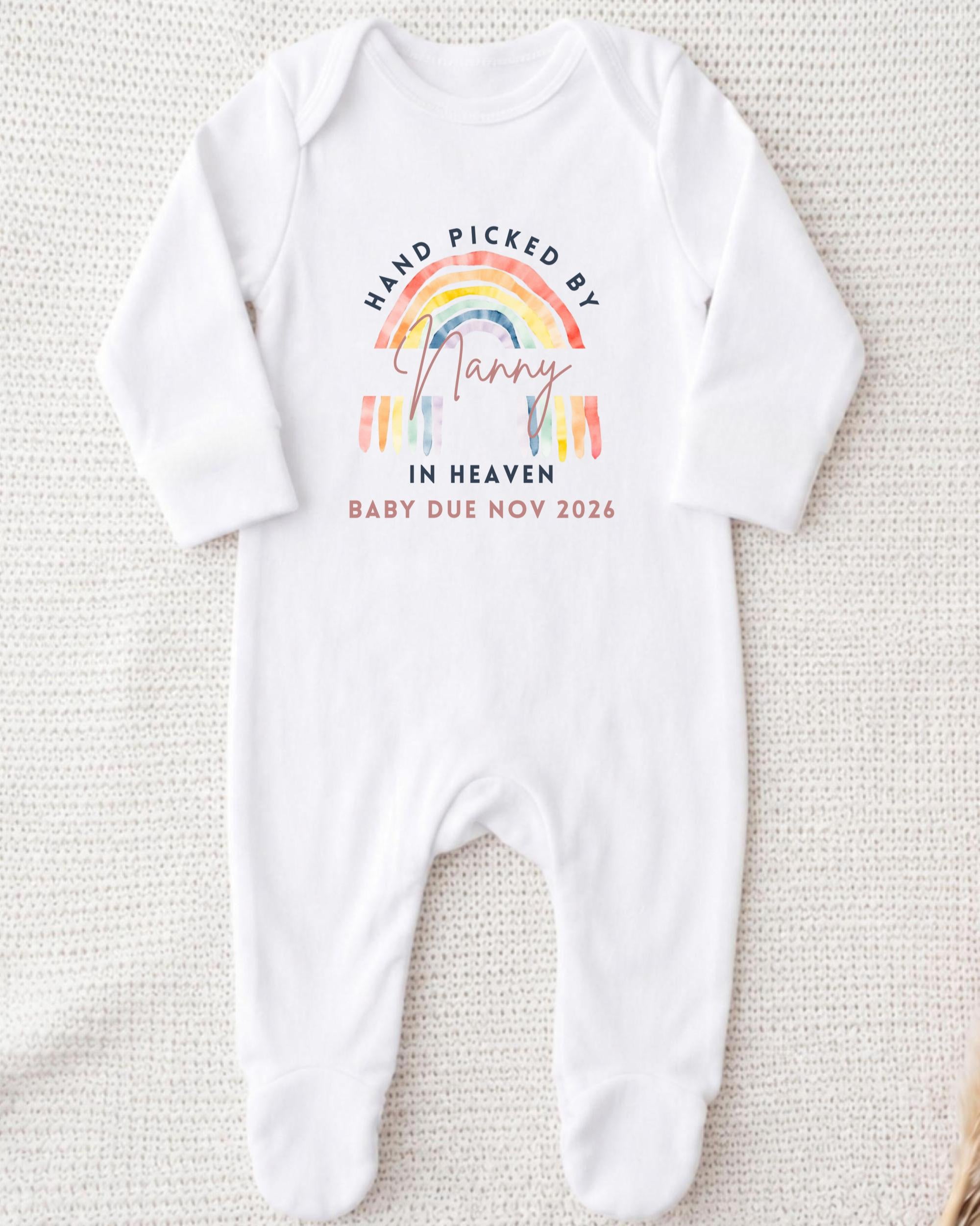 A white onesie with a rainbow graphic and text that reads "Hand picked by Nancy in Heaven Baby due Nov 2026".