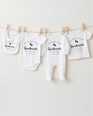 A row of white baby clothes hanging on a clothesline, with the text "Get ready to be Grandparents" printed on them.