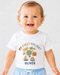 A smiling baby boy wearing a white t-shirt with a graphic design and text printed on it.