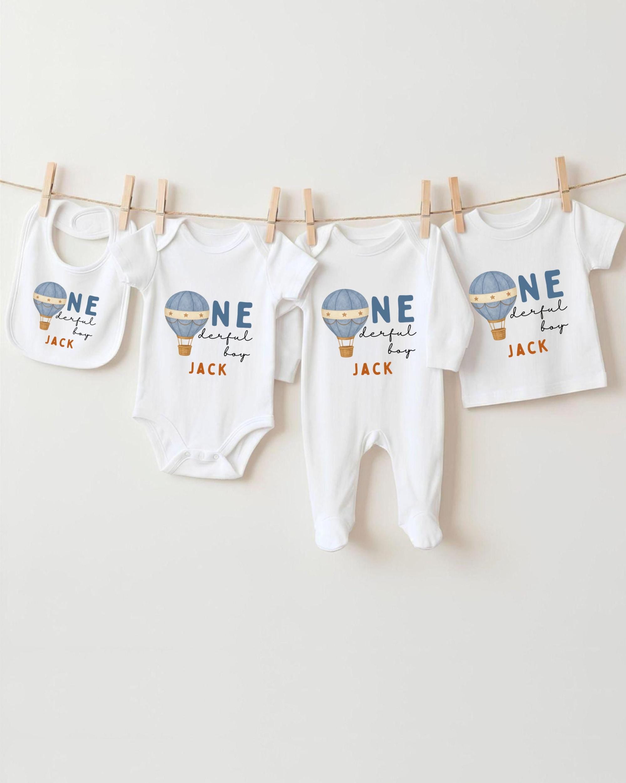 A collection of baby clothes, including onesies and pants, hanging on a clothesline.