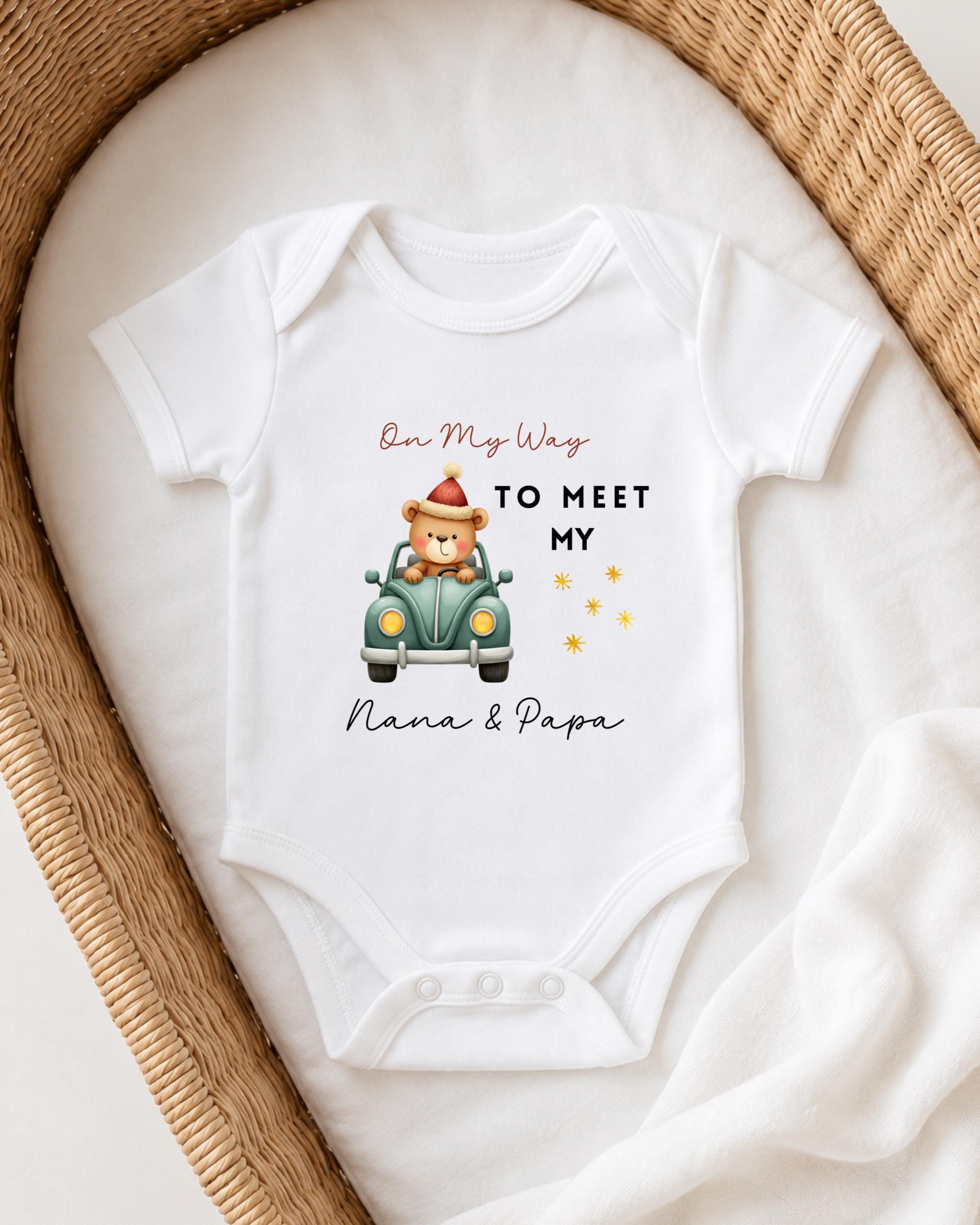 A white onesie with a teddy bear and a car graphic, along with the text "On My Way to Meet My Nana & Papa".