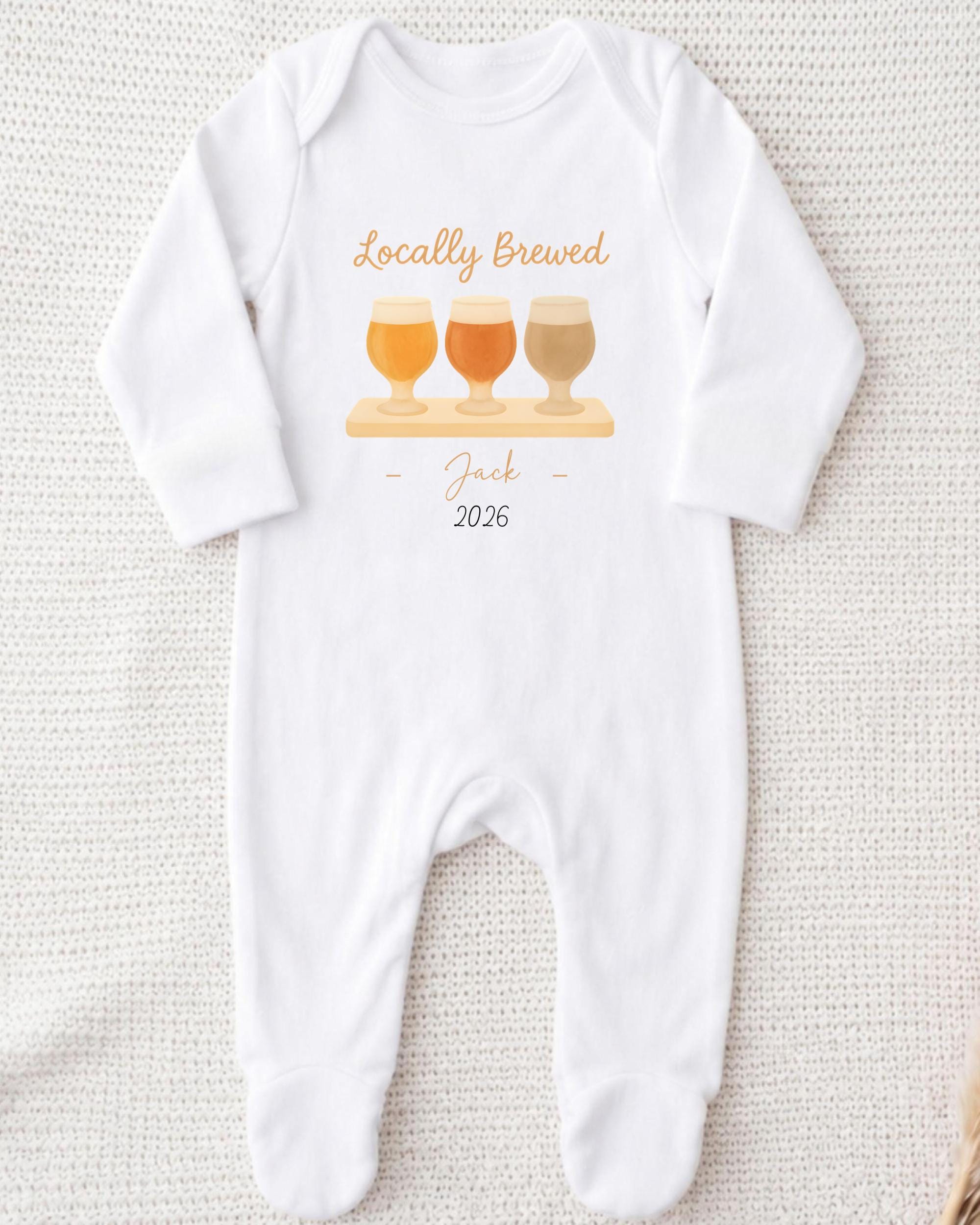 A white onesie with a graphic design of three beer glasses and the text "Locally Brewed Jack 2026" printed on it.