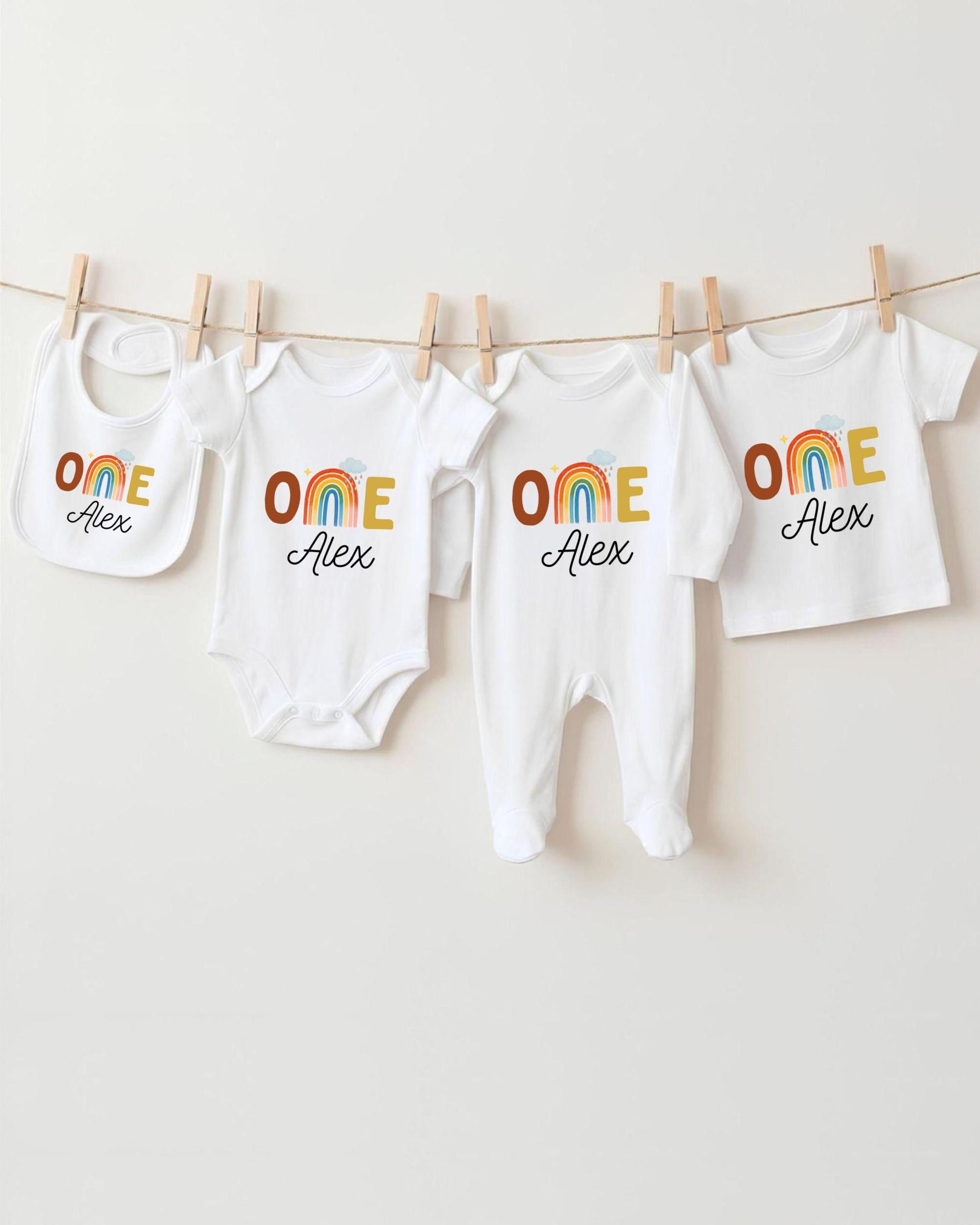 A collection of white baby clothes, including onesies and bibs, hanging on a clothesline.