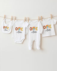 A collection of white baby clothes, including onesies and bibs, hanging on a clothesline.