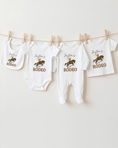 A collection of baby clothes, including bodysuits and rompers, hanging on a clothesline.