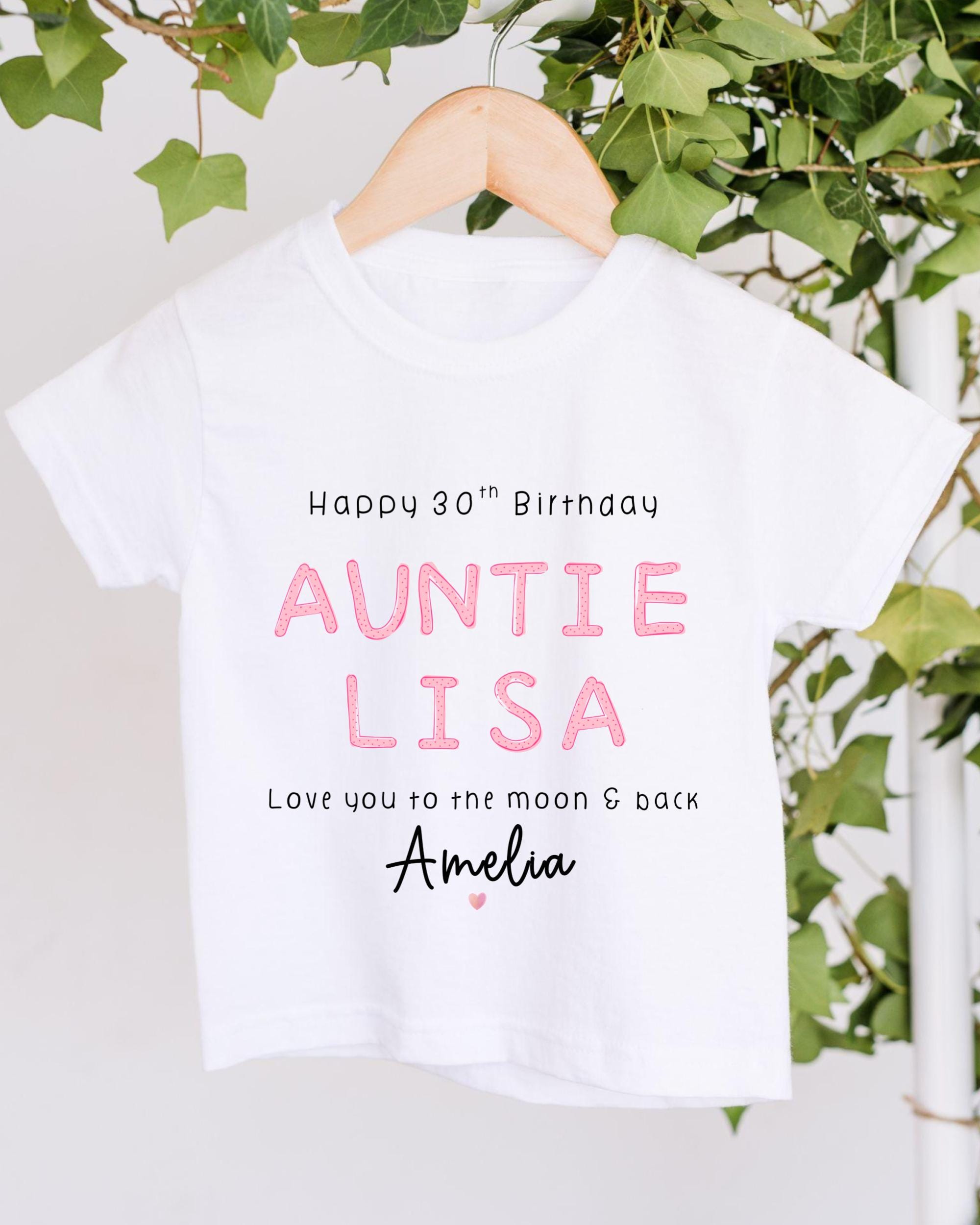A white t-shirt with text printed on it, hanging on a wooden hanger.