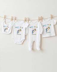 A row of white baby clothes with the text "One-DER the sea" printed on them, along with the name "Joshua" printed below.