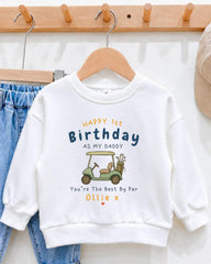 A white sweatshirt with a golf cart graphic and text printed on it, hanging on a wooden hanger.