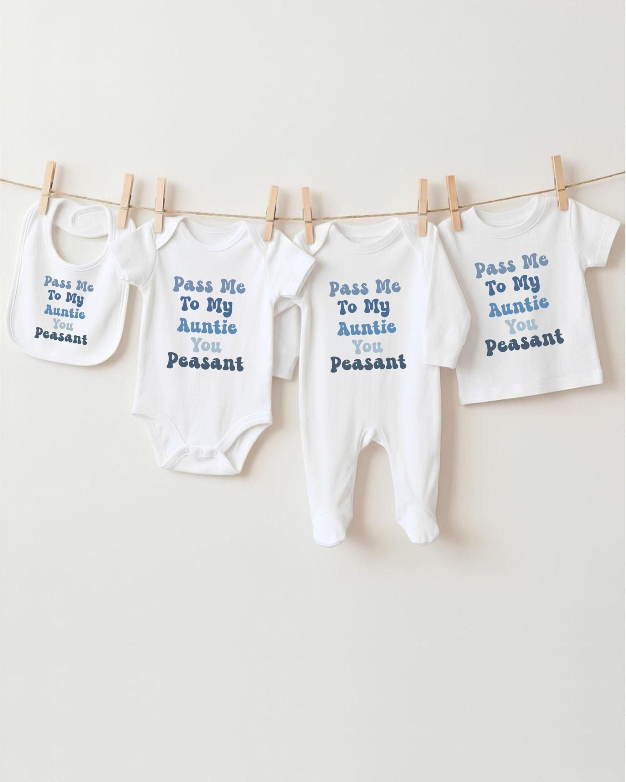 a row of four white baby clothes hanging on a clothesline, each with a different message printed on it.