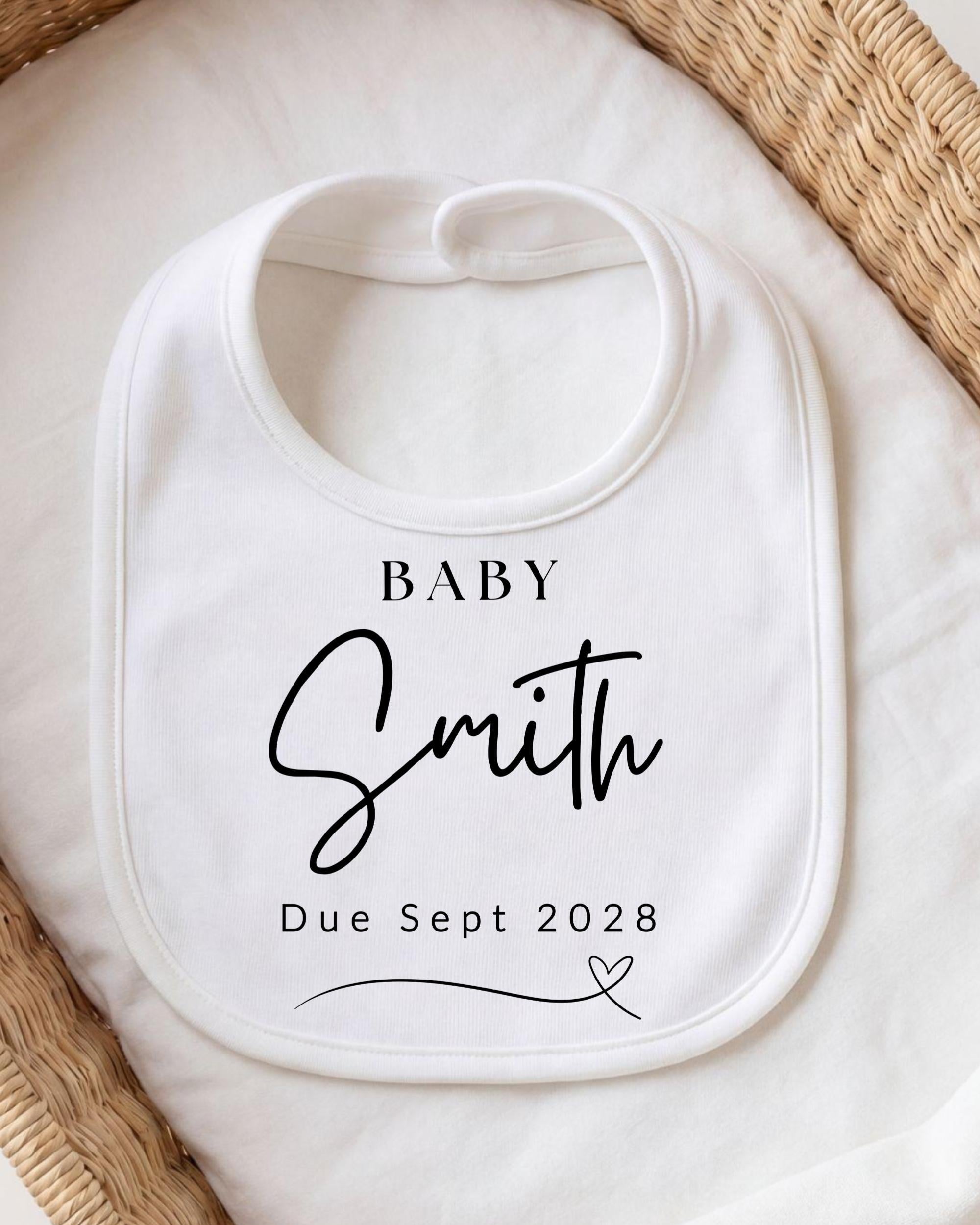 A white baby bib with personalized text and a date printed on it.