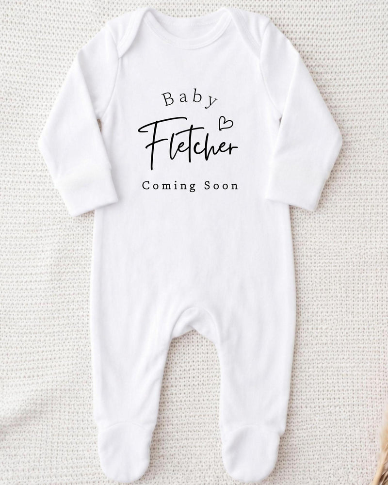 A white bodysuit with the text "Baby Fetter" and "Coming Soon" printed on it.