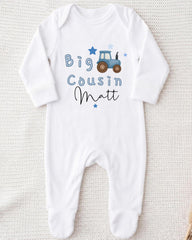 A white onesie with a tractor graphic and the text "Big Cousin Matt" printed on it.