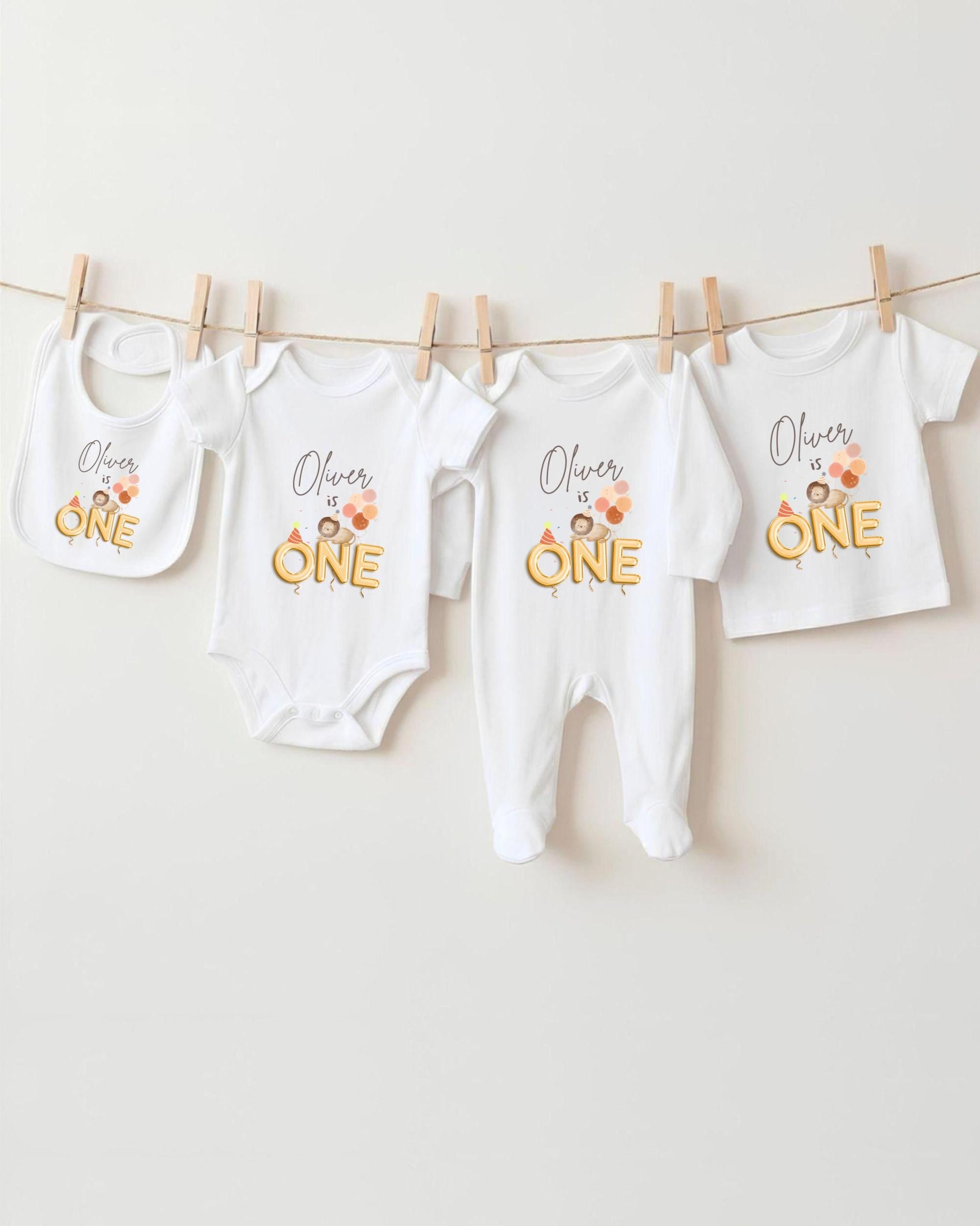 A collection of white baby clothes, including onesies and bibs, hanging on a clothesline.