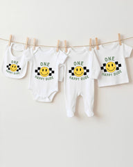 A collection of four white baby clothes with a checkered pattern and the text "ONE happy dude" printed on them, along with a bib featuring a smiling face.