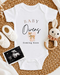 a baby announcement, including a white onesie with the text "BABY Owens" and a deer graphic, a crocheted rabbit toy, and a baby announcement.