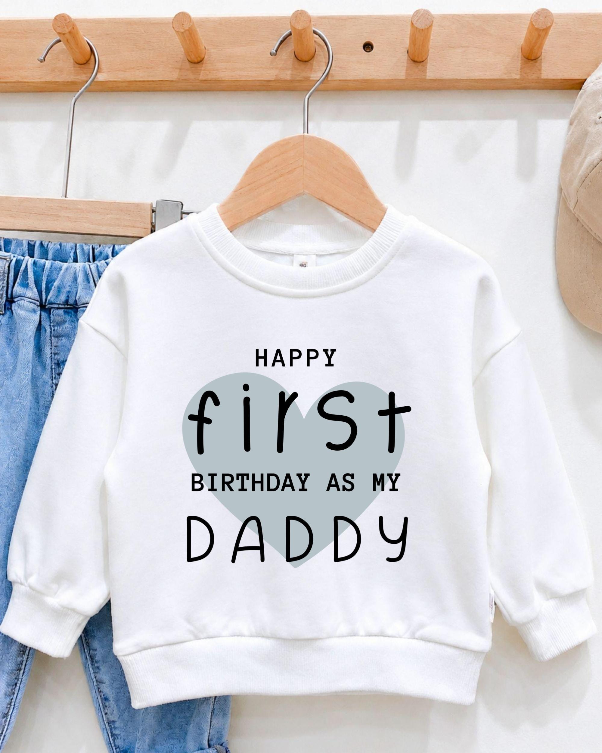 A white sweatshirt with a heart-shaped design and text printed on it, hanging on a wooden hanger.