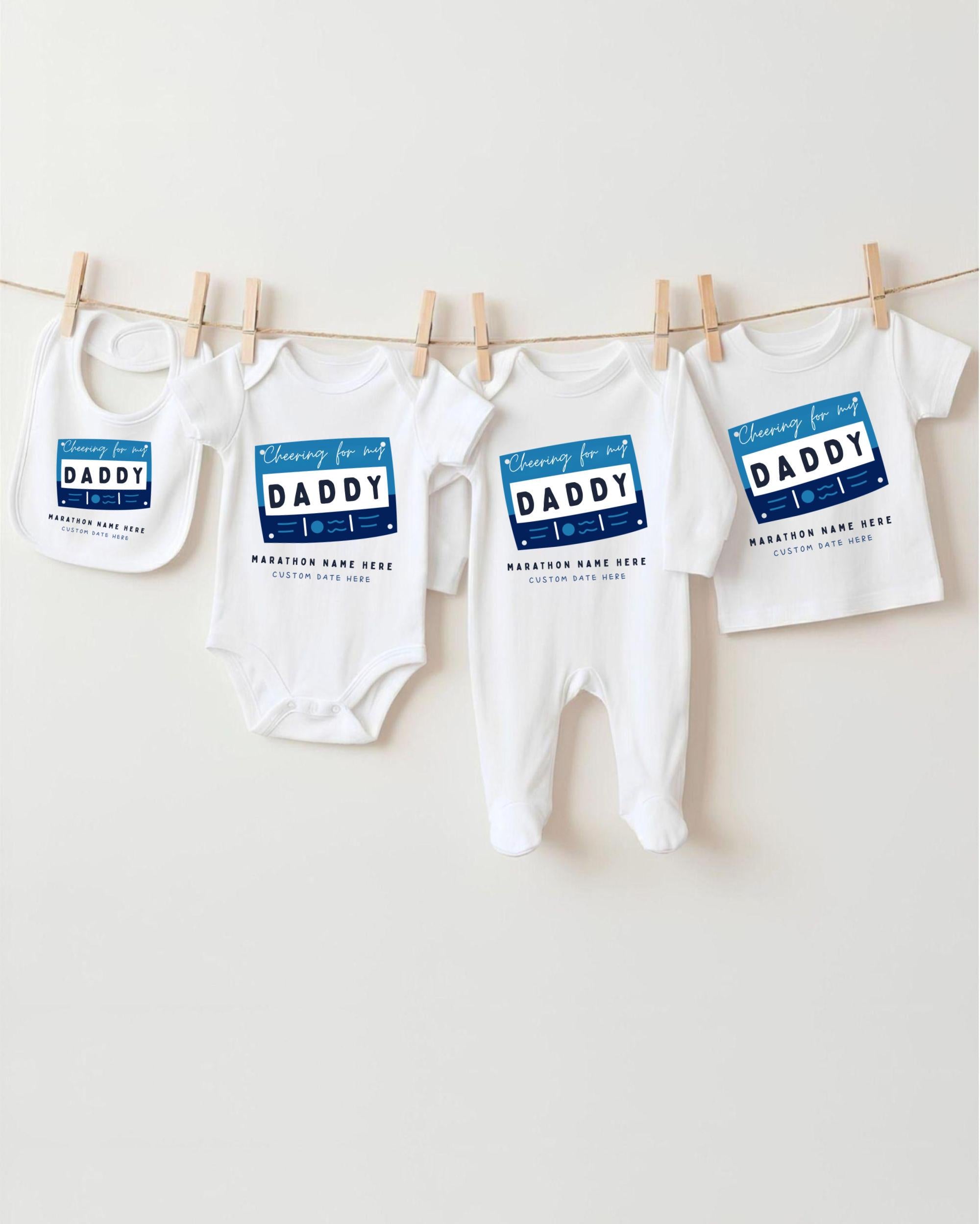 A row of four white baby clothes with blue text and graphics, hanging on a clothesline.
