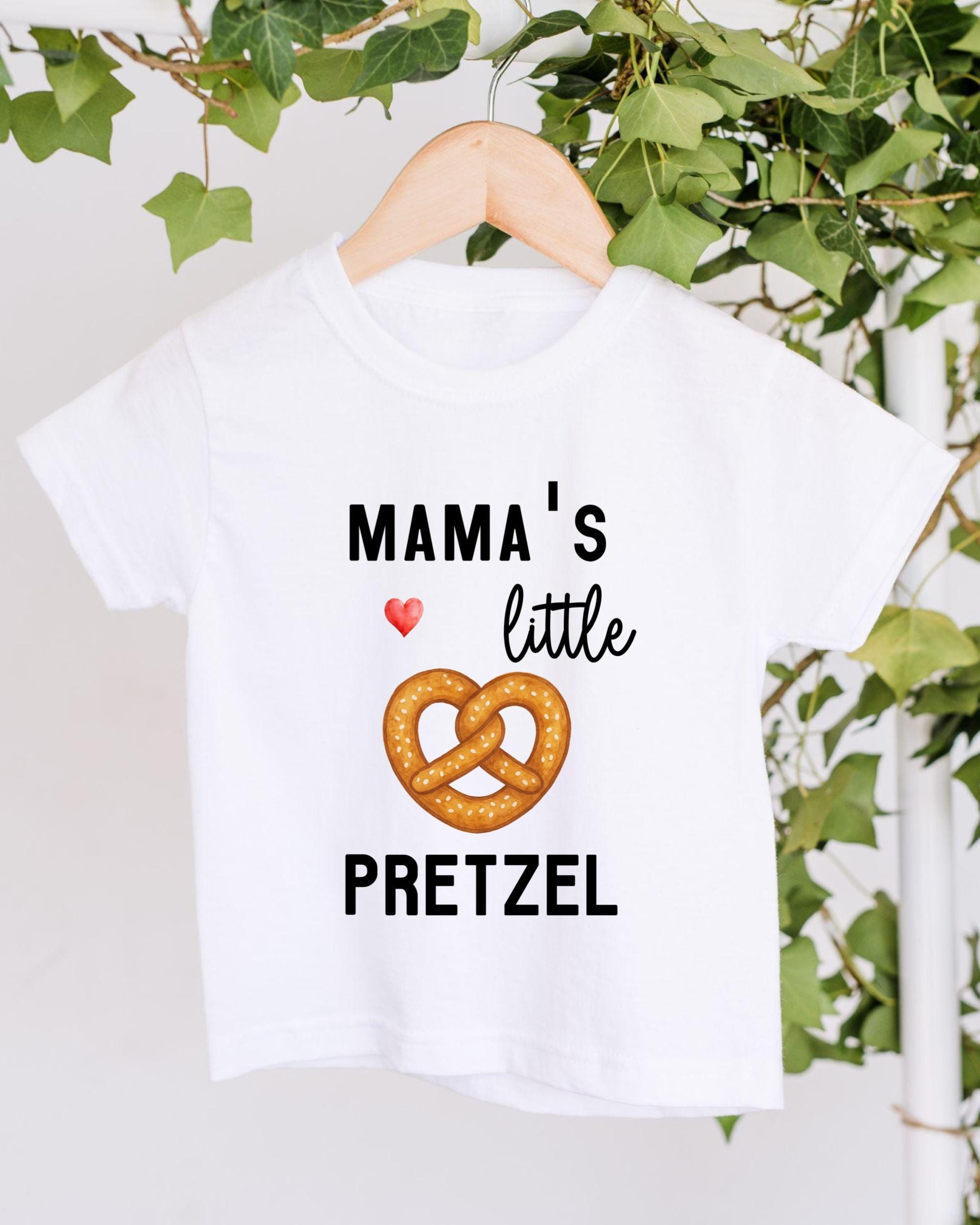 A white t-shirt with a graphic design featuring a pretzel and the text "Mama's little pretzel" printed on it.